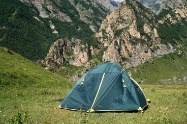 Kamp alanındaki yeşil çadır. Doğada dinlen. Yeşil çayırda kamp yapmak. Dağda kamp yapmak. Seyahat yaşam tarzı konsept macera yaz tatilleri açık hava yürüyüş ekipmanları.