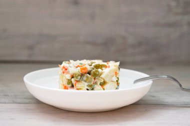 Beyaz bir tabakta bezelye filizleriyle süslenmiş Olivier salatası. Geleneksel Yeni Yıl ve Noel Rus salatası.