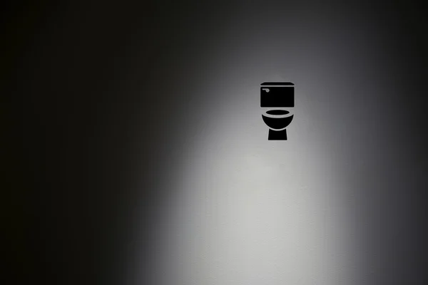 Символ туалета в подсветке бетонной стены . — стоковое фото