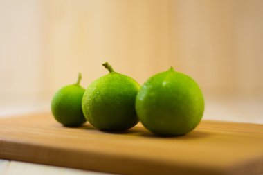 Ahşap kesme tahtası üzerinde üç limon renk.