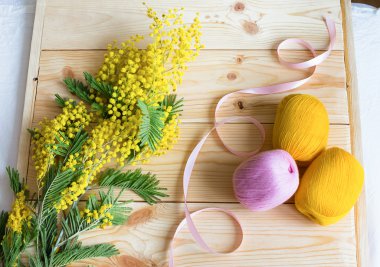 Mimoza ahşap arka plan üzerinde pembe bir kurdele ve iplik bobin ile sapı