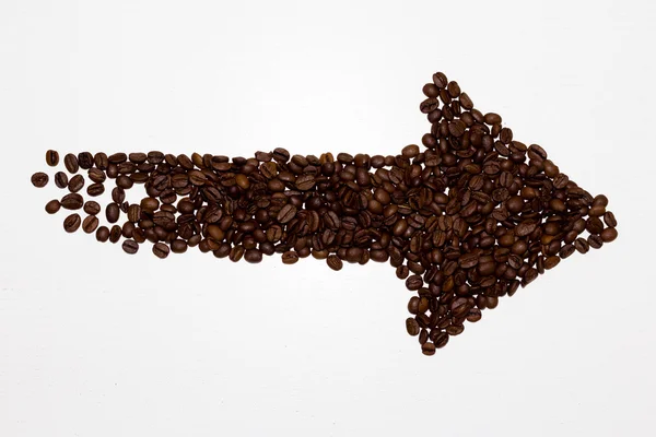 Arrow from coffee beans laid out on a beige background — Stock Photo, Image