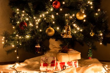 Noel hediyelerini dekore edilmiş gerlyandoy, parlak sarı ve kırmızı topları Noel ağacı altında