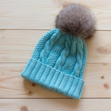 Mavi kapak yün el ile Kutup tilkisi doğal ahşap arka plan üzerinde bir kürk ponpon ile bağlı.