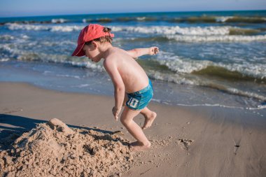Deniz kıyısında oynayan küçük çocuk