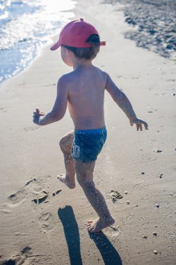 Deniz kıyısında oynayan küçük çocuk