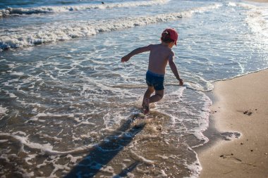 Deniz kıyısında oynayan küçük çocuk