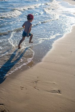 Deniz kıyısında oynayan küçük çocuk