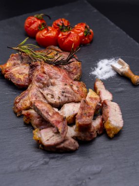Siyah tahtada domuz eti ve ızgara domates tuzu.