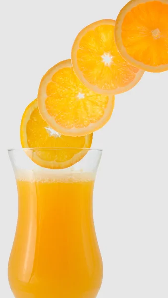 Jugo de naranja en el flujo lateral de vidrio y rodajas de naranja — Foto de Stock