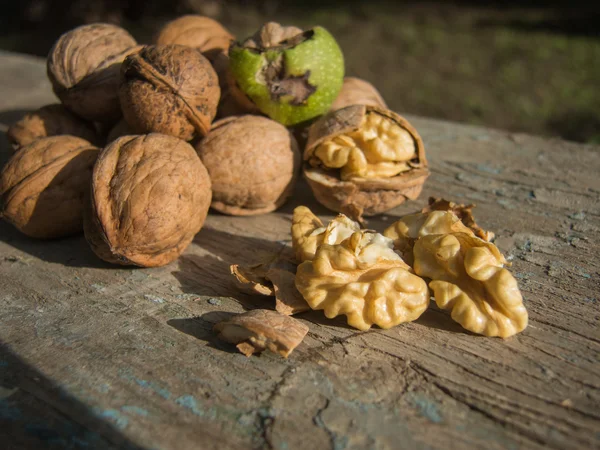 Pile of walnuts and cracked walnut kernels on a wooden chair — Stok fotoğraf