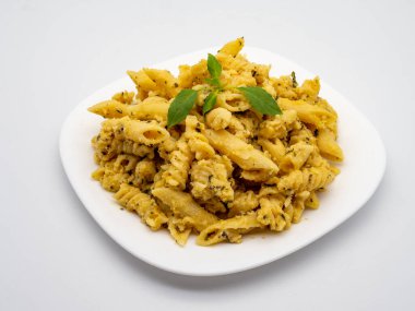 Beyaz tabakta fesleğen yaprağı ile süslenmiş makarna dörtlüsü karışımı.