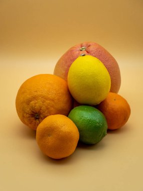 Turuncu arka planda çeşitli turunçgil meyveleri