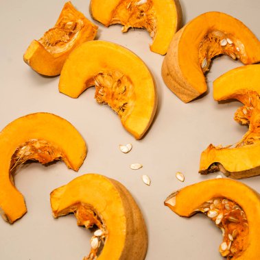 Çekirdekli sarı balkabağı parçaları beyaz masanın üzerinde yatıyor. Seçici odak