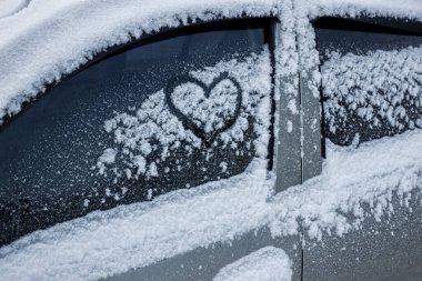 Kalp karla kaplı arabada cama boyanır.