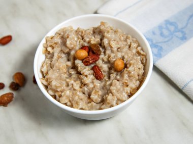 Kahverengi fındıklı yulaf ezmesi beyaz tabakta fındık ve peçetenin yanında..