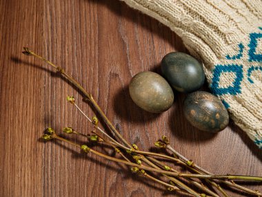 Boyalı yumurtalar, yeşil böbrekli söğüt dalları örülmüş ceketle kahverengi sıraların üzerinde uzanır..