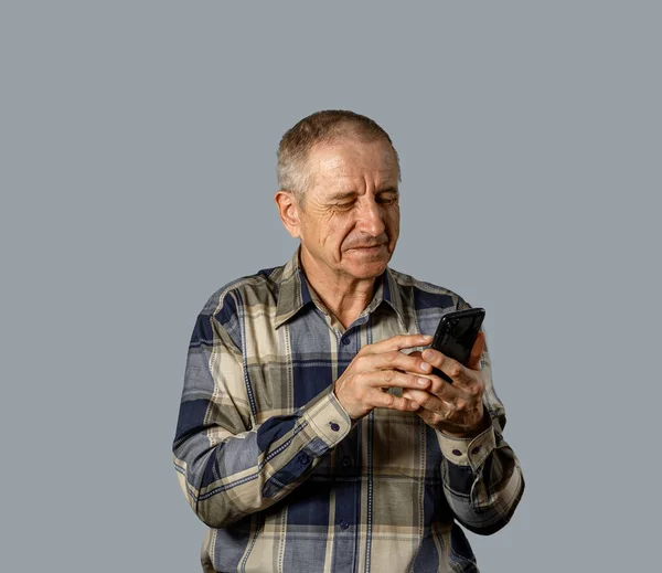 Kareli gömlekli yaşlı adam, abonenin numarasını akıllı telefondan arıyor..