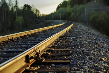 Demiryolu rayları gün batımı güneşiyle aydınlanır..