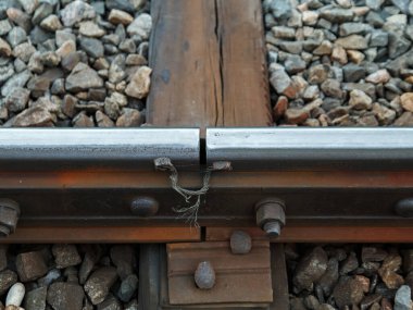 Demiryolundaki iki demiryolunun kesiştiği yerde tahtadan yataklı vagonlar ve taşlar var..