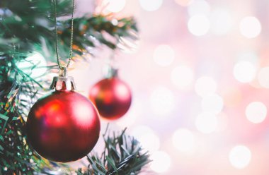 Noel süsü. Çam dallarında asılı kırmızı toplar Noel ağacı çelengi ve soyut bokeh arka planında fotokopi ile süslenmiş süsler.
