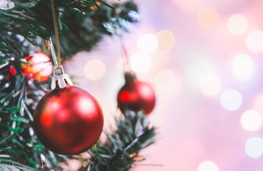 Noel süsü. Çam dallarında asılı kırmızı toplar Noel ağacı çelengi ve soyut bokeh arka planında fotokopi ile süslenmiş süsler.