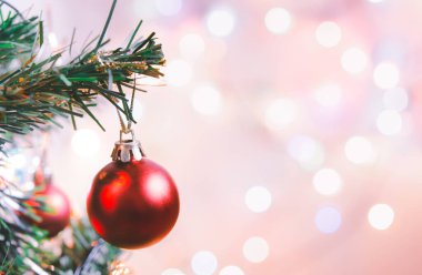 Noel süsü. Çam dallarında asılı kırmızı toplar Noel ağacı çelengi ve soyut bokeh arka planında fotokopi ile süslenmiş süsler.