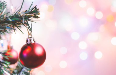 Noel süsü. Çam dallarında asılı kırmızı toplar Noel ağacı çelengi ve soyut bokeh arka planında fotokopi ile süslenmiş süsler.