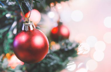 Noel süsü. Çam dallarında asılı kırmızı toplar Noel ağacı çelengi ve soyut bokeh arka planında fotokopi ile süslenmiş süsler.