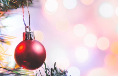 Noel süsü. Çam dallarında asılı kırmızı toplar Noel ağacı çelengi ve soyut bokeh arka planında fotokopi ile süslenmiş süsler.