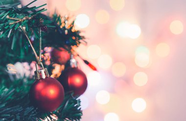 Noel süsü. Çam dallarında asılı kırmızı toplar Noel ağacı çelengi ve soyut bokeh arkaplanının üzerinde fotokopi alanı olan süsler