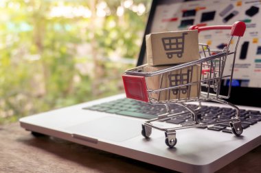 İnternetten alışveriş konsepti - Paket ya da kağıt kutular içinde alışveriş arabası logosu ve dizüstü bilgisayarda klavye. İnternet 'te alışveriş servisi. Eve teslimat teklif ediyor