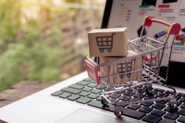 İnternetten alışveriş konsepti - Paket ya da kağıt kutular içinde alışveriş arabası logosu ve dizüstü bilgisayarda klavye. İnternet 'te alışveriş servisi. Eve teslimat teklif ediyor