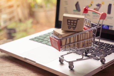 İnternetten alışveriş konsepti - Paket ya da kağıt kutular içinde alışveriş arabası logosu ve dizüstü bilgisayarda klavye. İnternet 'te alışveriş servisi. Eve teslimat teklif ediyor