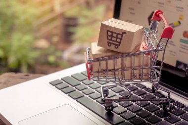 İnternetten alışveriş konsepti - Paket ya da kağıt kutular içinde alışveriş arabası logosu ve dizüstü bilgisayarda klavye. İnternet 'te alışveriş servisi. Eve teslimat teklif ediyor