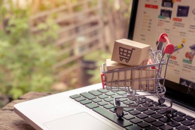 İnternetten alışveriş konsepti - Paket ya da kağıt kutular içinde alışveriş arabası logosu ve dizüstü bilgisayarda klavye. İnternet 'te alışveriş servisi. Eve teslimat teklif ediyor