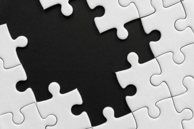 Siyah arkaplanda bitmemiş beyaz yapboz parçaları