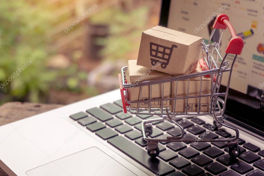 Shopping online concept - Parcel or Paper cartons with a shopping cart logo in a trolley on a laptop keyboard. Shopping service on The online web. offers home delivery