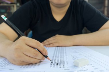 Kadın öğrenciler, cevap kağıtları ve matematik soru kağıtları üzerinde seçilmiş kalemle yazı yazıyorlar. Sınav yapan öğrenciler. okul sınavı
