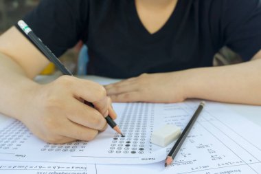 Kadın öğrenciler, cevap kağıtları ve matematik soru kağıtları üzerinde seçilmiş kalemle yazı yazıyorlar. Sınav yapan öğrenciler. okul sınavı