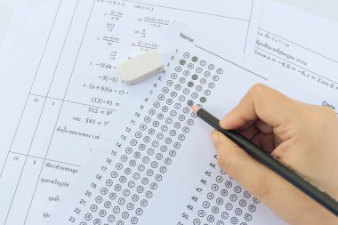 Öğrenciler, cevap kağıtları ve matematik soru kağıtları üzerinde seçilmiş kalemle yazı yazma seçeneğini el ele tutuyorlar. Sınav yapan öğrenciler. okul sınavı