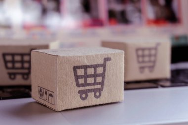 İnternetten alışveriş. Laptop klavyesinde alışveriş arabasının logosu olan karton kutu. İnternet 'te alışveriş servisi. Eve teslimat teklif ediyor