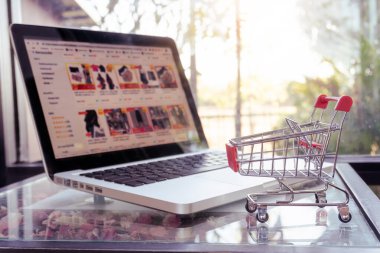 Çevrimiçi alışveriş konsepti - alışveriş arabası veya tramvay ve masadaki dizüstü bilgisayar