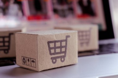 İnternetten alışveriş. Laptop klavyesinde alışveriş arabasının logosu olan karton kutu. İnternet 'te alışveriş servisi. Eve teslimat teklif ediyor