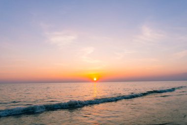 Gün batımı yansıma denizi. Bulutların ardında güzel bir gün batımı ve deniz manzarasının üstünde mavi bir gökyüzü.