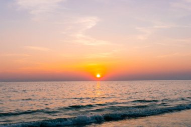 Gün batımı yansıma denizi. Bulutların ardında güzel bir gün batımı ve deniz manzarasının üstünde mavi bir gökyüzü.