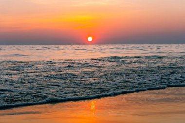 Gün batımı yansıma denizi. Bulutların ardında güzel bir gün batımı ve deniz manzarasının üstünde mavi bir gökyüzü.