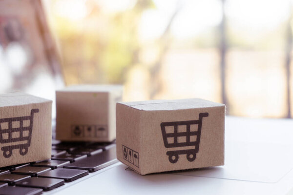 Интернет-магазины. Картонная коробка с логотипом корзины на клавиатуре ноутбука. Сервис покупок в Интернете. доставка на дом