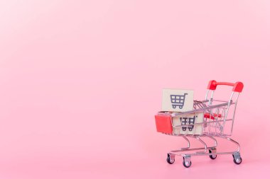 Alışveriş konsepti: pembe arka planda kırmızı alışveriş arabasında karton kutular veya karton kutular. Çevrimiçi alışveriş tüketicileri evden ve teslimat servisinden alışveriş yapabilirler. kopyalama alanı ile