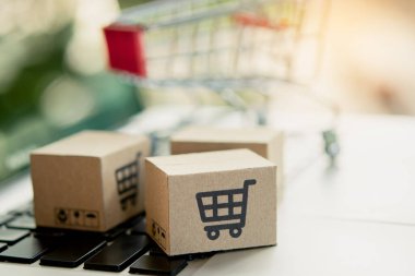İnternetten alışveriş. Laptop klavyesinde alışveriş arabasının logosu olan karton kutu. İnternet 'te alışveriş servisi. Eve teslim etmeyi teklif ediyor. Boşluğu kopyala